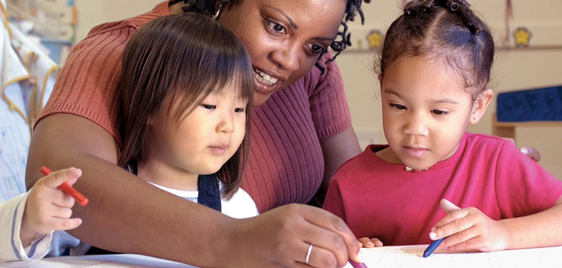 Image of teacher helping two kindergarten students