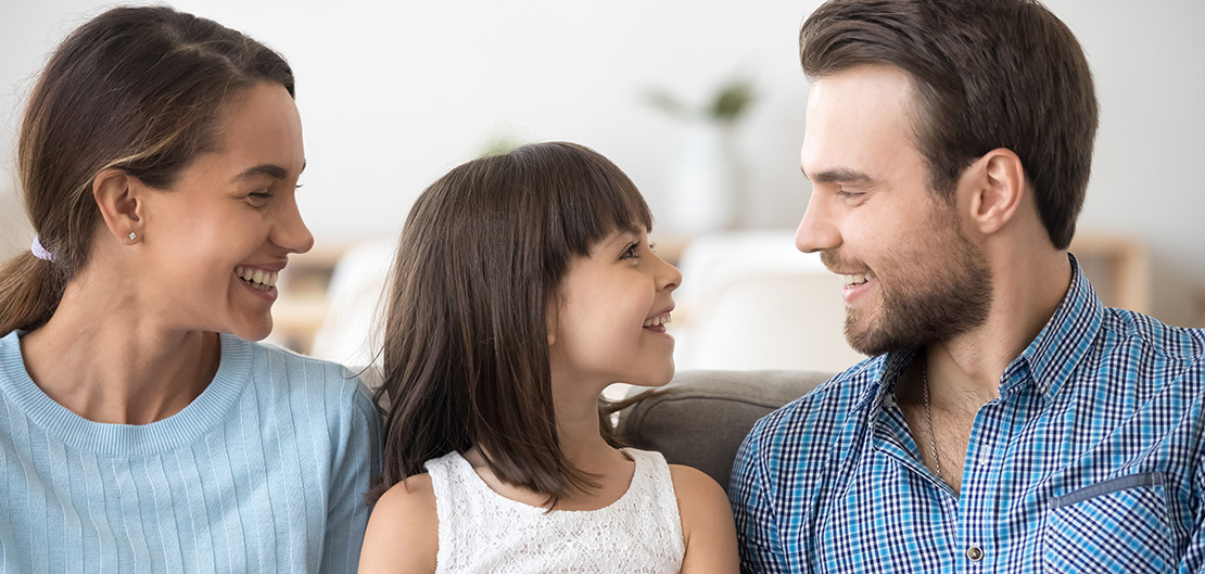 Image of smiling child sitting between smiling parents