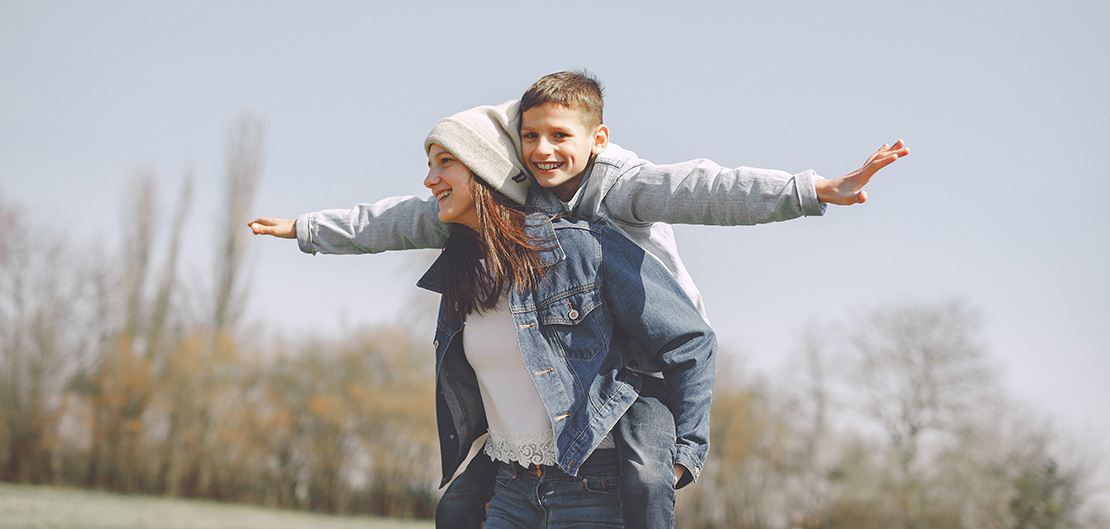Image of woman giving a child a piggyback ride.